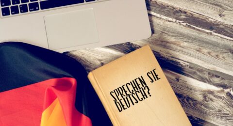 بهترین کتاب برای یادگیری زبان آلمانی روی میز چوبی با یادداشت‌های مطالعه و یک خودکار